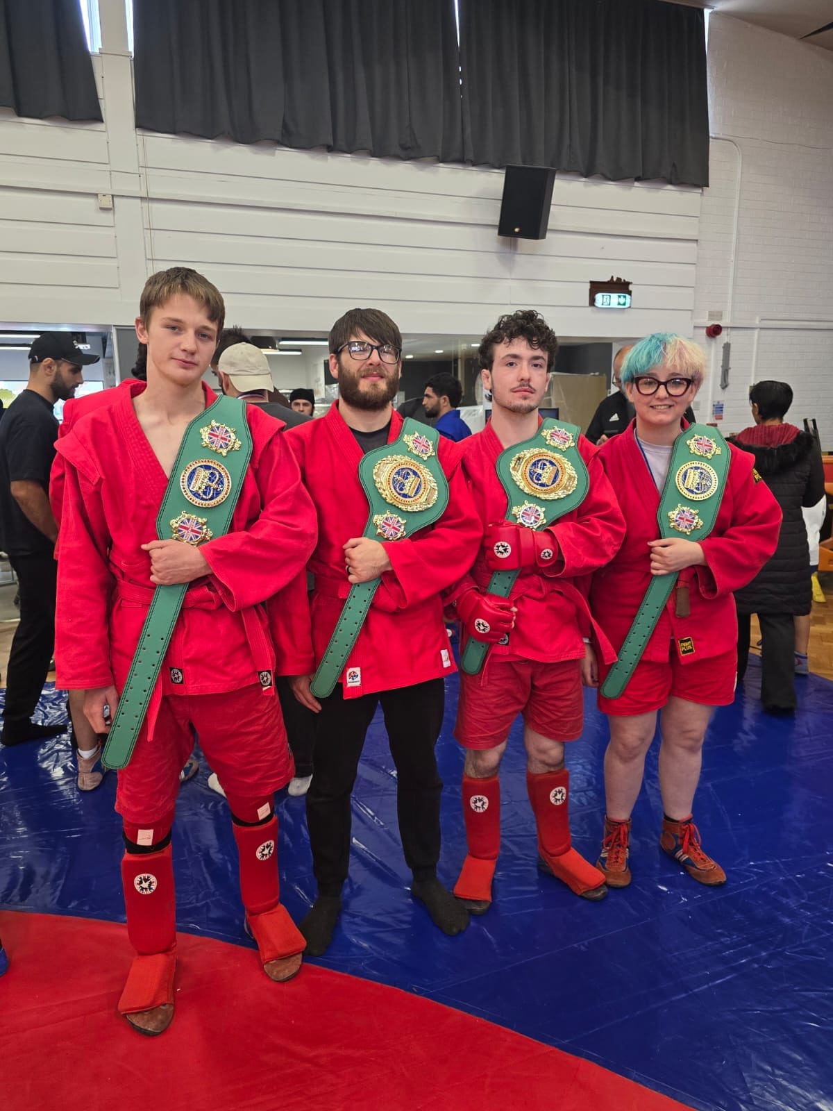 Four Doncaster Sambo and Wrestling competitors wearing red kit and holding their British championship belts