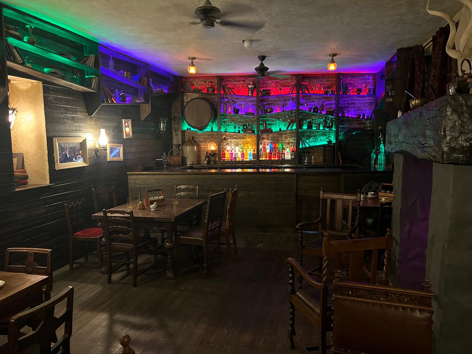 Wooden tables and illuminated bottles inside The Twisted Broom in Doncaster